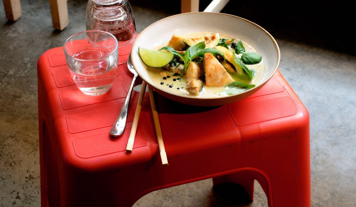Curry vert Wild Rice servi dans une assiette creuse, sur un tabouret rouge